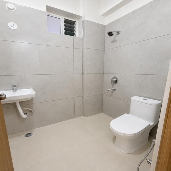 Bathroom, modern bathroom, minimalist bathroom, compact bathroom, contemporary bathroom, bathroom interior, clean bathroom, tiled bathroom, beige tiles, gray tiles, wall tiles, floor tiles, ceramic tiles, shower area, showerhead, wall-mounted shower, shower faucet, chrome fixtures, bathroom sink, wash basin, pedestal sink, white sink, toilet, western toilet, modern toilet, toilet seat, bathroom drain, floor drain, small window, ventilation window, bathroom fittings, plumbing fixtures, neutral colors, beige interior, light gray walls, white fixtures, simple design, functional bathroom, apartment bathroom, residential bathroom, compact space, clean interior, modern home, contemporary design, minimalist decor, tiled floor, tiled walls, indoor plumbing, hygienic space, bathroom photography.